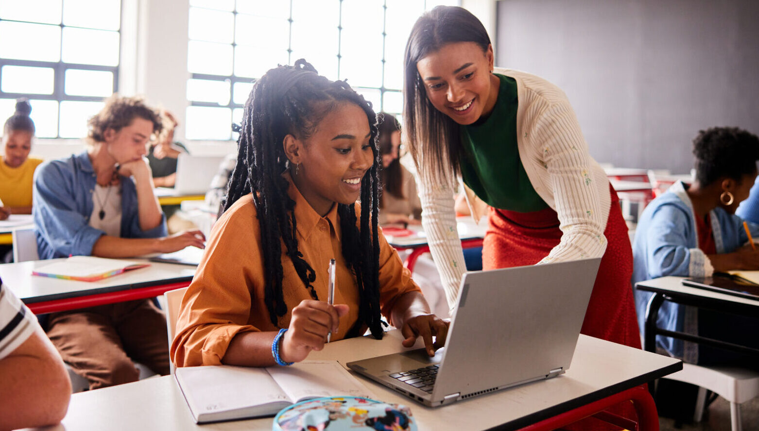 Teacher supporting pupils using laptops in the classroom